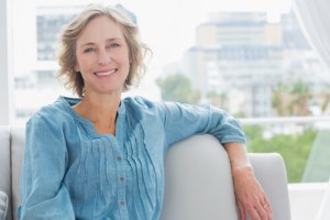 Patient smiling in chair, learning why nerve repositioning may be needed before her dental implant procedure by Irvine oral surgeon.